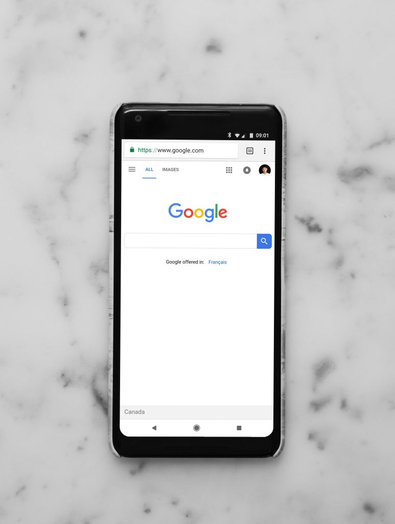 Smartphone displaying Google search interface on a marble surface, illustrating the significance of mobile optimization in digital marketing strategies.