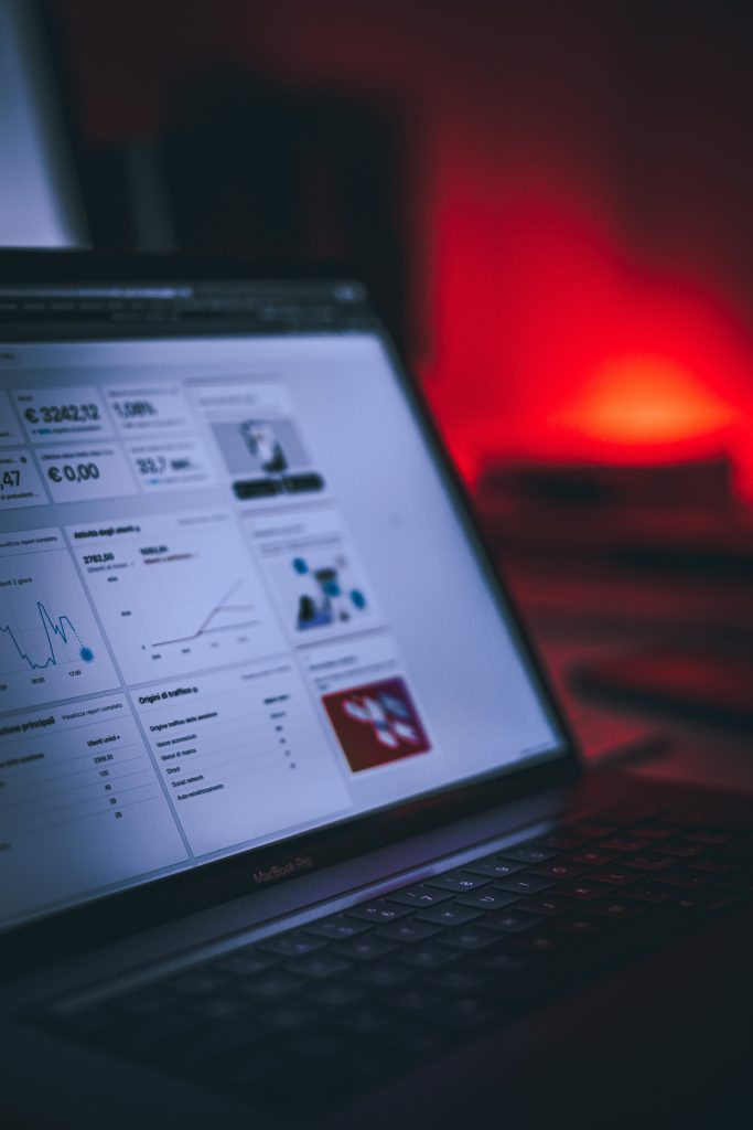 Laptop displaying digital marketing analytics dashboard with graphs and metrics in a dimly lit environment.