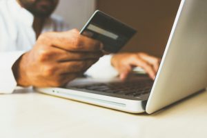 Person holding a credit card while using a laptop, illustrating e-commerce optimization and online shopping experience.